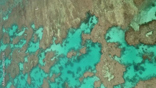 Aerial orbit above coral reefs in crystal clear waters of Isle of Pines, New Caledonia. vertical format photo