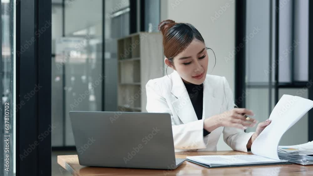 Asian woman sitting in a corporate office, business woman working, finance and accounting employees preparing financial statements, money management of a startup company. Asian woman sitting in a corporate office, business woman working, finance and accounting employees preparing financial statements, money management of a startup company.