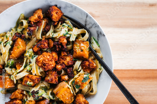 plant-based fettuccine pasta with spinach pumpkin and tofu chunks photo