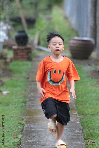 A young boy in an orange shirt playing outside in a resort. 