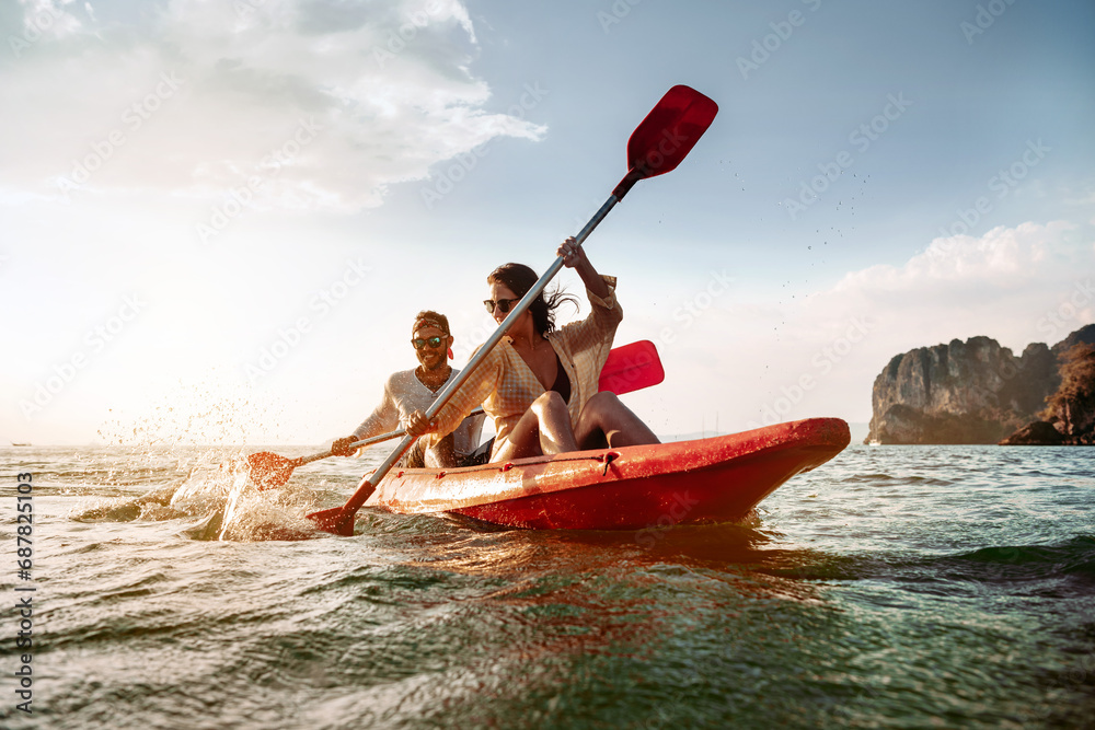 Happy couple walks by sea kayak or canoe at tropical bay - obrazy, fototapety, plakaty 