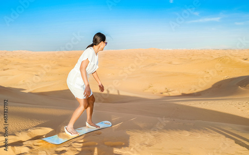 Young women sand surfing at the sand dunes of Dubai United Arab Emirates