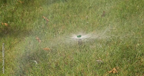 Automatic Sprinkler Watering Lush Green Grass in a Sprawling Field photo