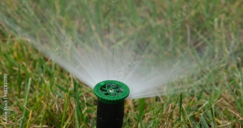 Automatic Sprinkler Watering Lush Green Grass in a Sprawling Field photo