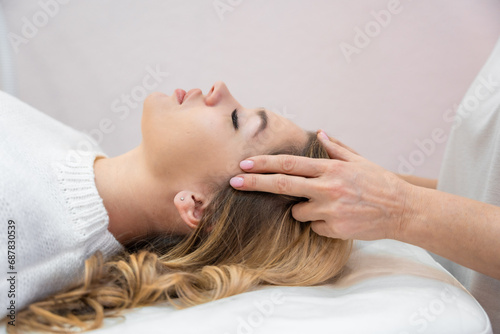 Healer performing by lightly touched set of 32 points of access bars on young woman head, stimulating positive change thoughts and emotions. Alternative medicine photo