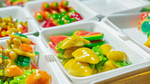 Thai dessert made from beans Molded into different shapes, glossy surface, various colors, mixed together in a clear plastic box. On the green artificial grass Suitable for use as a background image
