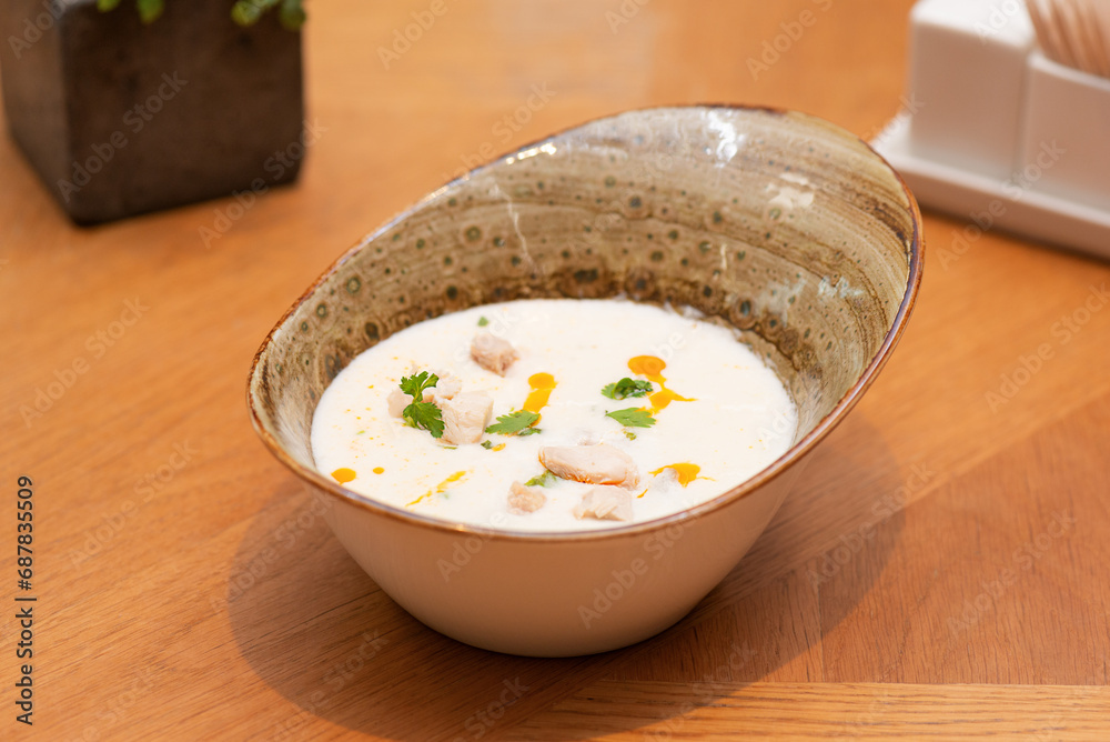 Tom Kha soup with coconut milk with chicken and herbs on a table, Thai cuisine. Vertical orientation, hard light. Tom Kha soup with coconut milk with chicken and herbs on a table, Thai cuisine. Vertical orientation, hard light.