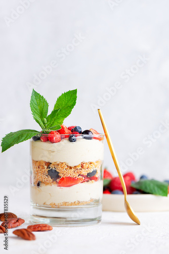 Parfait in a glass with berries, mint, whipped cream and biscuit. Healthy food, vegan, sugar, gluten and lactose free.
