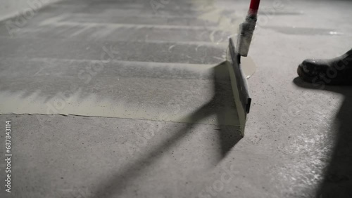 The process of priming a floor with a solution. Waterproofing concrete floor. Industrial primer. The process of priming the floor with a liquid solution using a spatula. photo