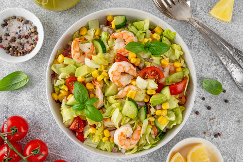 Shrimp salad with vegetables and olive oil mustard dressing. Fresh seafood salad in a bowl on a gray concrete background. Healthy food. Copy space.