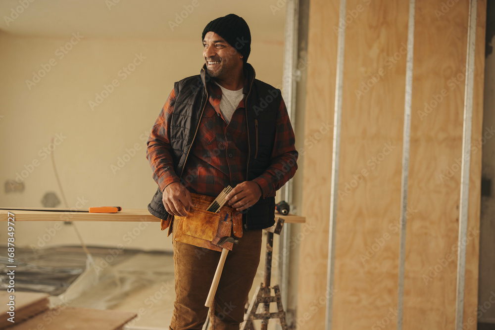 © Jacob Lund - Smiling construction worker in tool belt upgrading home interior © Jacob Lund - Smiling construction worker in tool belt upgrading home interior