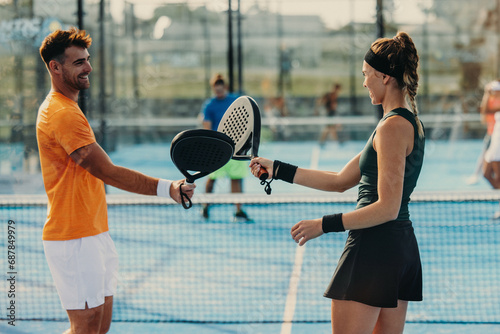 Padel team players tapping rackets in a mixed doubles game photo