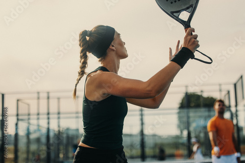 Female padel athlete raising her racket with a firm grip, preparing to hit a smash