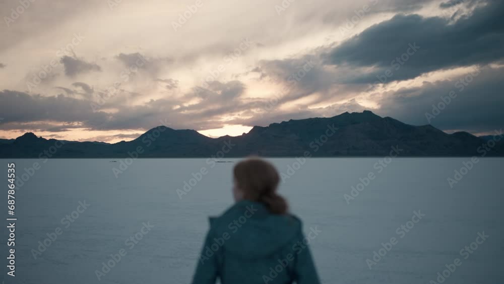 Young woman enjoying beautiful sunset and Mountain View in the Great Salt Flats Young woman enjoying beautiful sunset and Mountain View in the Great Salt Flats