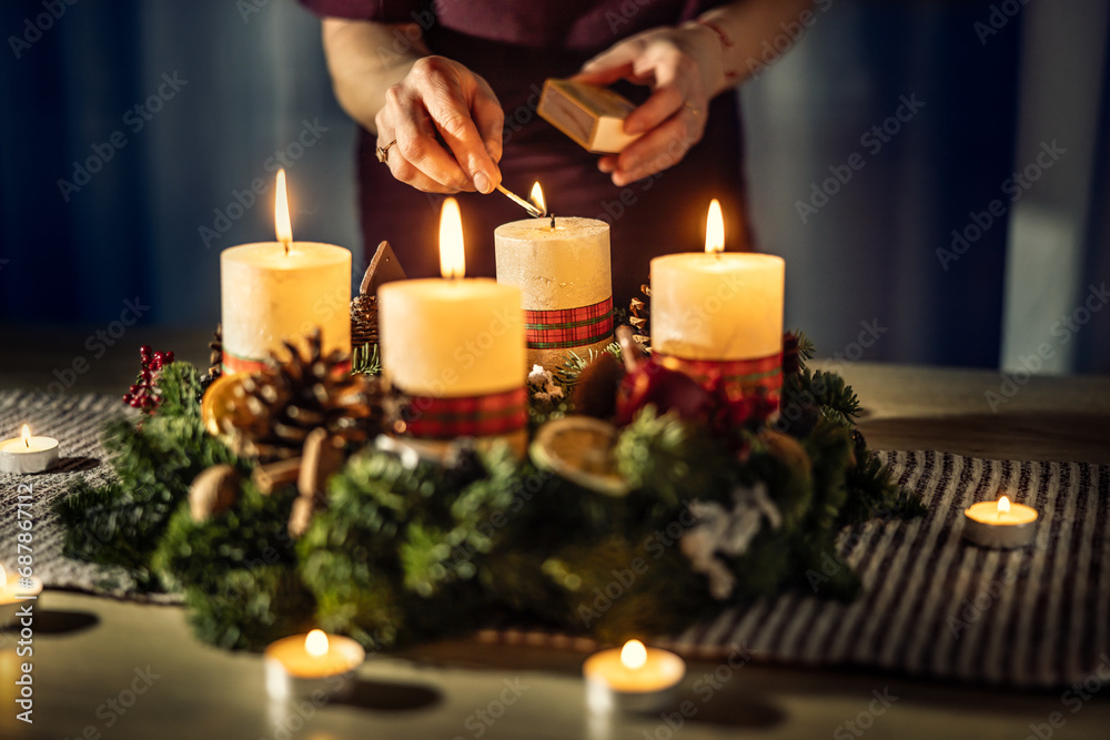 A woman lights the last fourth candle on an Advent wreath during Christmas Eve