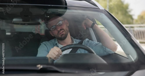 Sad angry man sitting in a car in a traffic jam and gesticulating angrily in impatience and irritation photo