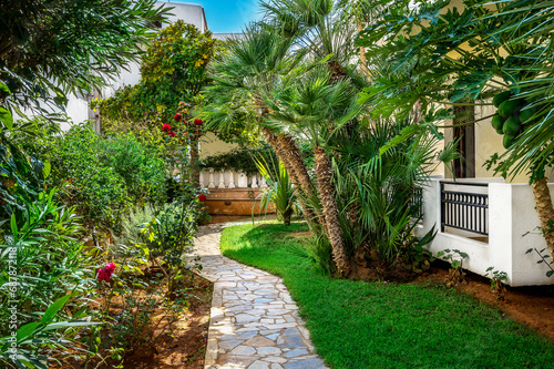 A tropical haven unfolds as a garden nestles next to the house, featuring lush Mediterranean plants. Ideal for travel brochures, gardening magazines and for projects seeking the perfect harmony.