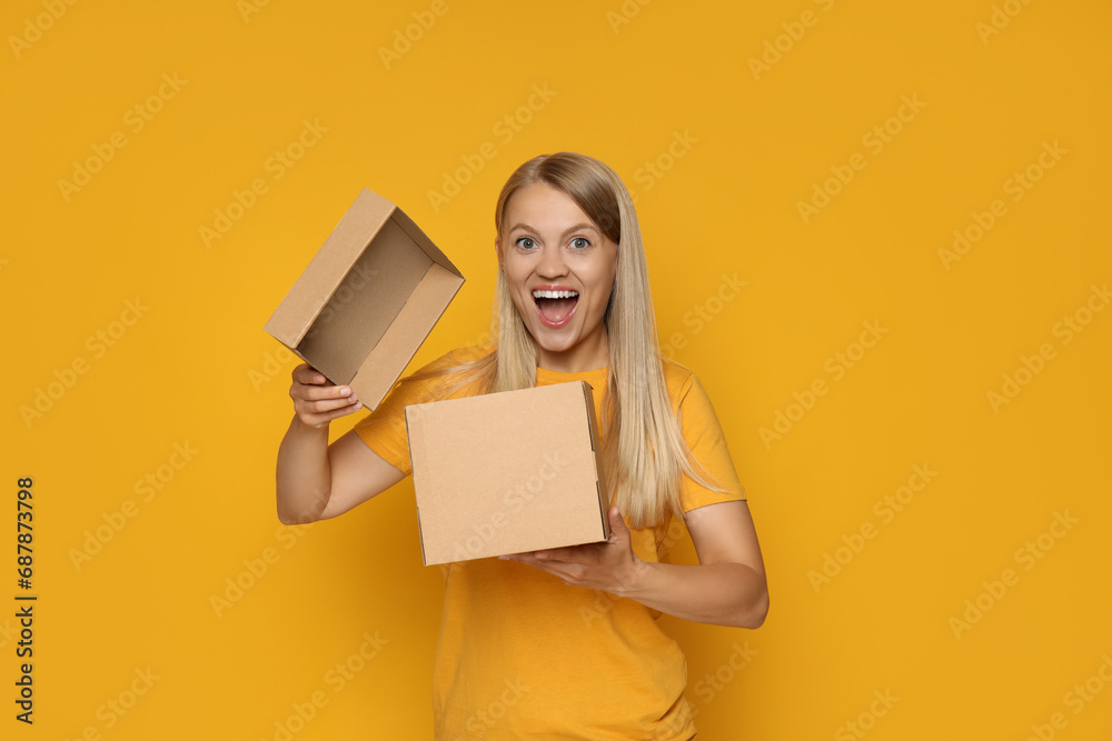 An attractive blonde looks into a cardboard box - obrazy, fototapety, plakaty 