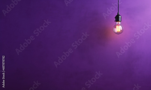 arrière plan violet uni avec une ampoule allumée qui pend photo