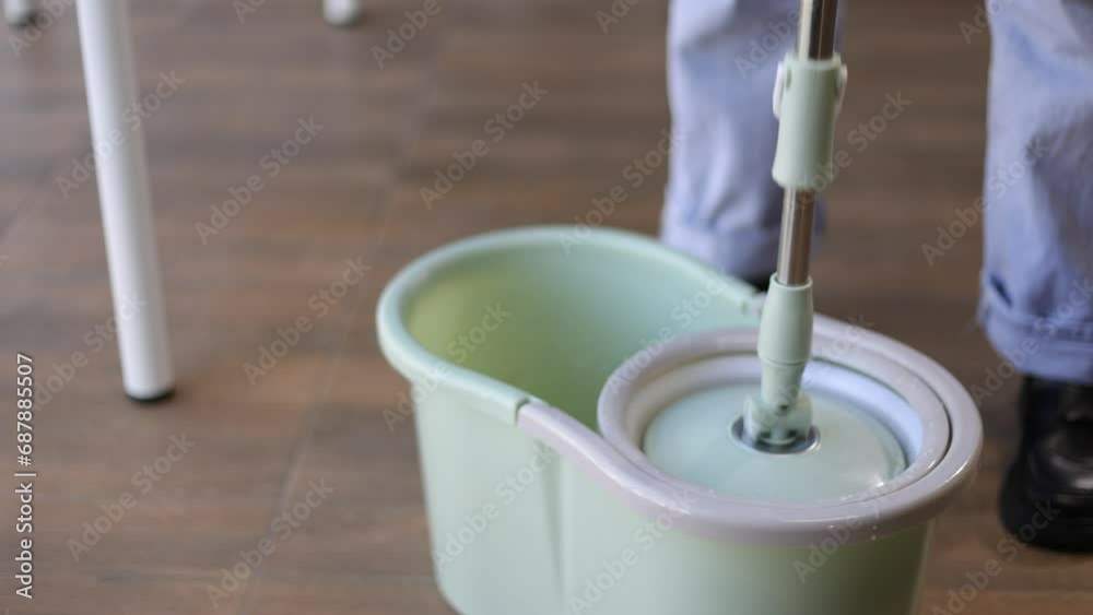 Cleaning worker is working with a mop in a bucket of water. Cleaning worker is working with a mop in a bucket of water.
