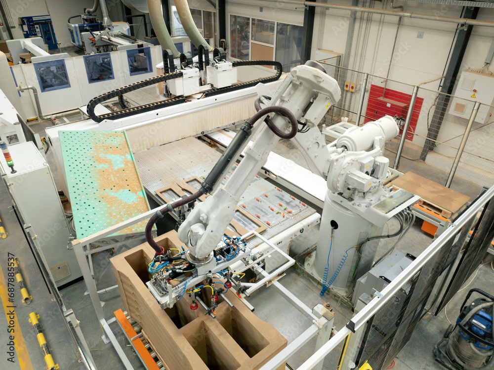 Industrial automation and robotics in modern industrial factory. High precision robotic arm assembling wooden furniture in big furniture manufacturing facility with industrial robotic manipulators.