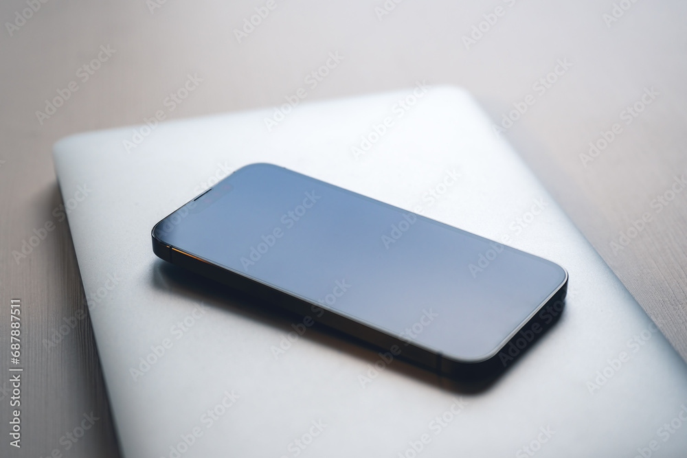 Smartphone and laptop computer on office desk, modern technology equipment necessary for business Smartphone and laptop computer on office desk, modern technology equipment necessary for business