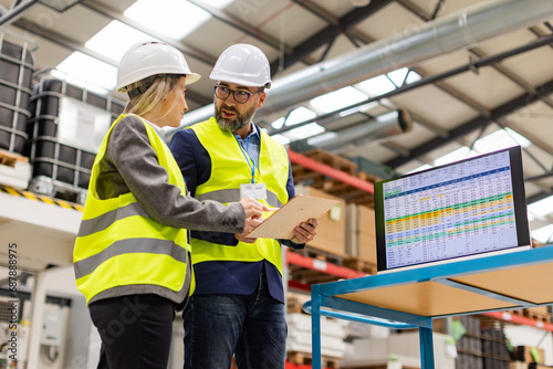 Female engineer and male project manager standing in modern industrial factory, talking about production. Team management in manufacturing facility