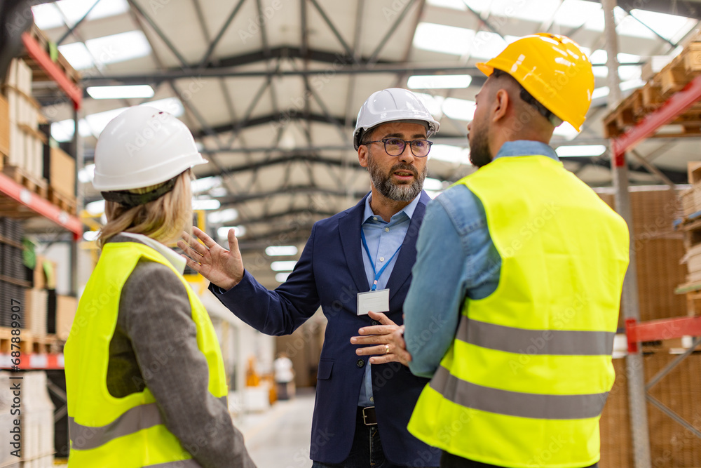 Engineers consulting with director in modern industrial factory, talking about new production project or investment. Team management in manufacturing facility. Engineers consulting with director in modern industrial factory, talking about new production project or investment. Team management in manufacturing facility.