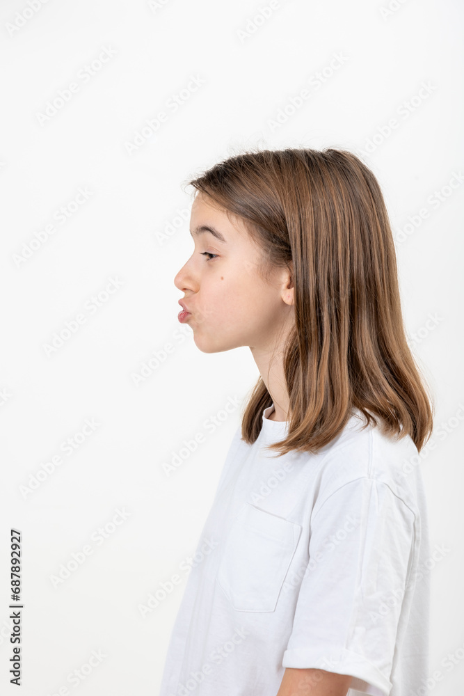A teenage girl grimaces with her lips pursed into a tube on a white background. A teenage girl grimaces with her lips pursed into a tube on a white background.