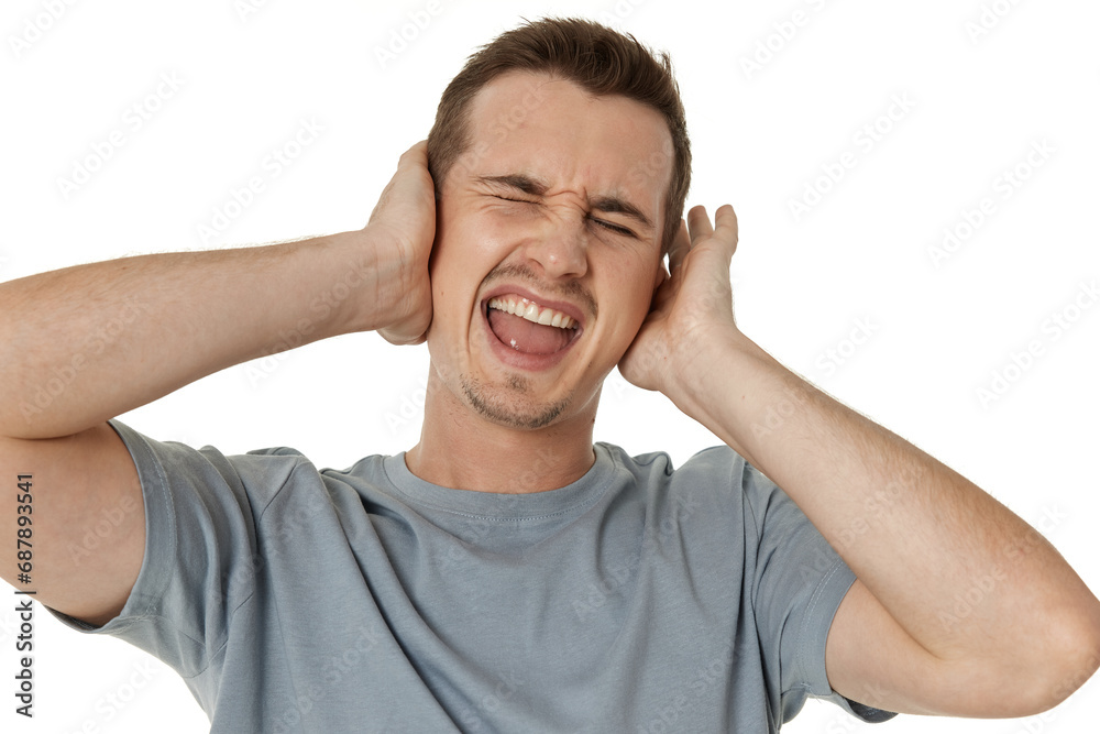 caucasian man in t-shirt covers ears with hands on white background caucasian man in t-shirt covers ears with hands on white background