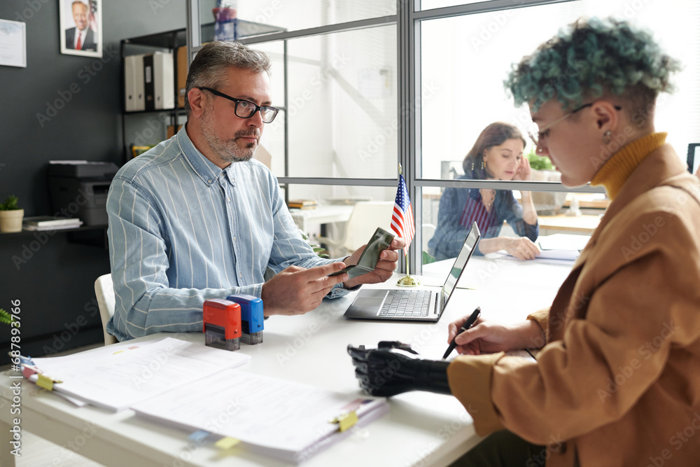 Woman with disability having meeting with manager in office while giving documents for visa Woman with disability having meeting with manager in office while giving documents for visa