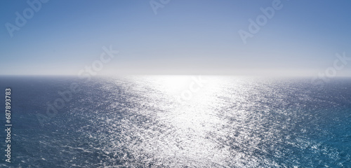 View across the coast to the ocean and horizon, sunshine in the water 