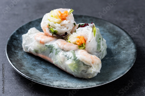 Vietnamese spring rolls with vegetables, rice noodles and prawns on black background