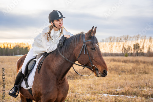 Beautiful blond professional female jockey riding a horse in field. Friendship with horse concept