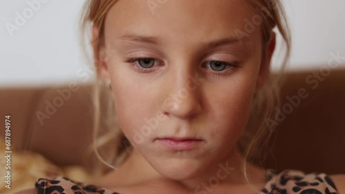 Close up of little girl face reading a book, fast reader, reading on sofa at home, big blue eyes reading, front view, slow motion