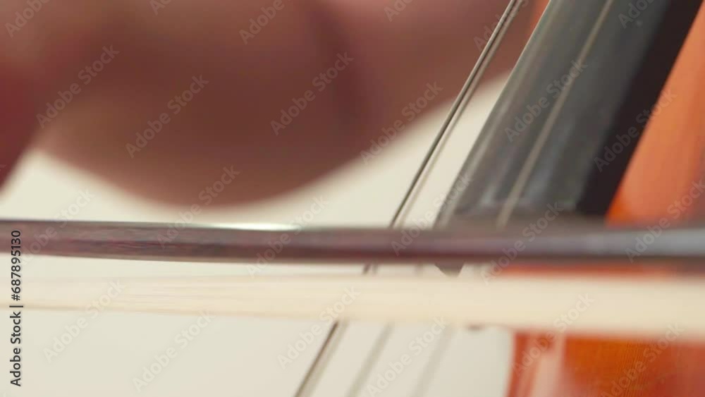 Close up of hand playing cello with cello bow. Classical Orchestral Musician. Close up of hand playing cello with cello bow. Classical Orchestral Musician.