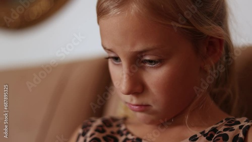 Close up of little girl face reading a book, fast reader, reading on sofa at home, big blue eyes reading 