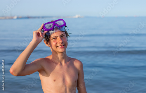 Teen joy: Handsome teenager smiles with a diving mask, capturing the carefree spirit of a summer day at the beach,copyspace.