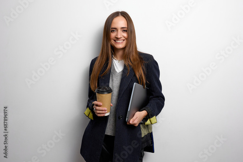 A well-groomed young woman with brown hair works in the business field and holds a laptop in her hands