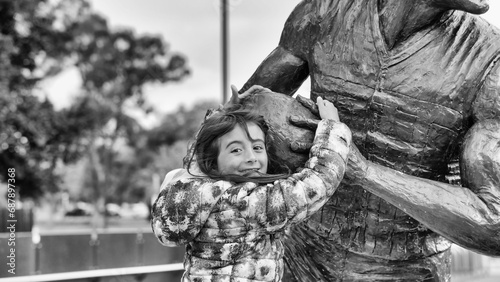 Happy young girl embracing a statue while on holiday