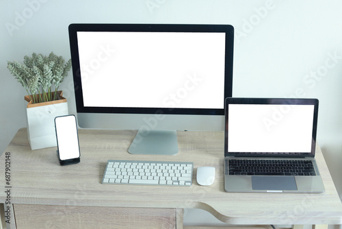 Mockup of laptop computer and mobile phone with white blank screen on office table