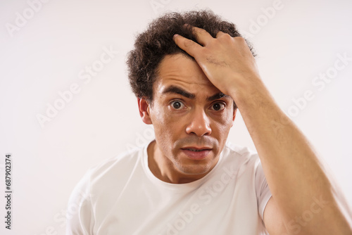 Handsome mixed race adult man is looking at wrinkles at his forehead.
