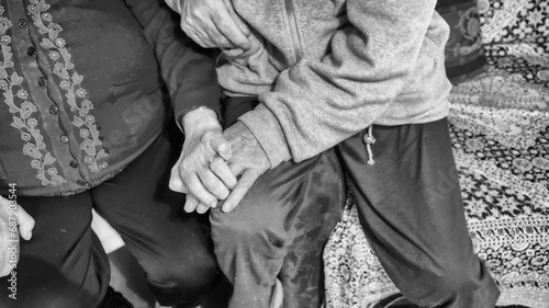 Two elderly seniors hand in hand at home