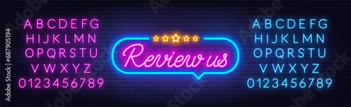 Review Us neon sign in the speech bubble on brick wall background.