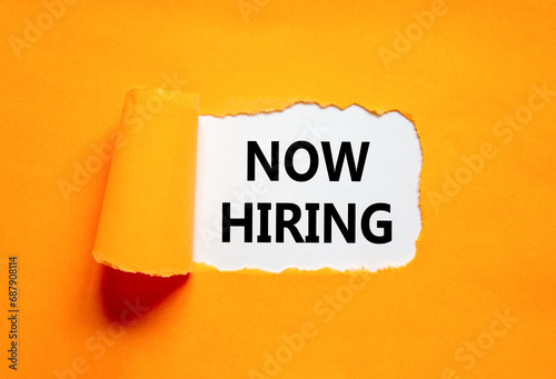 Now hiring symbol. Concept words Now hiring on beautiful white paper. Beautiful orange table orange background. Business marketing, motivational now hiring concept. Copy space.