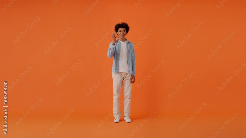 Man demonstrating broad smile and making OK signs in studio