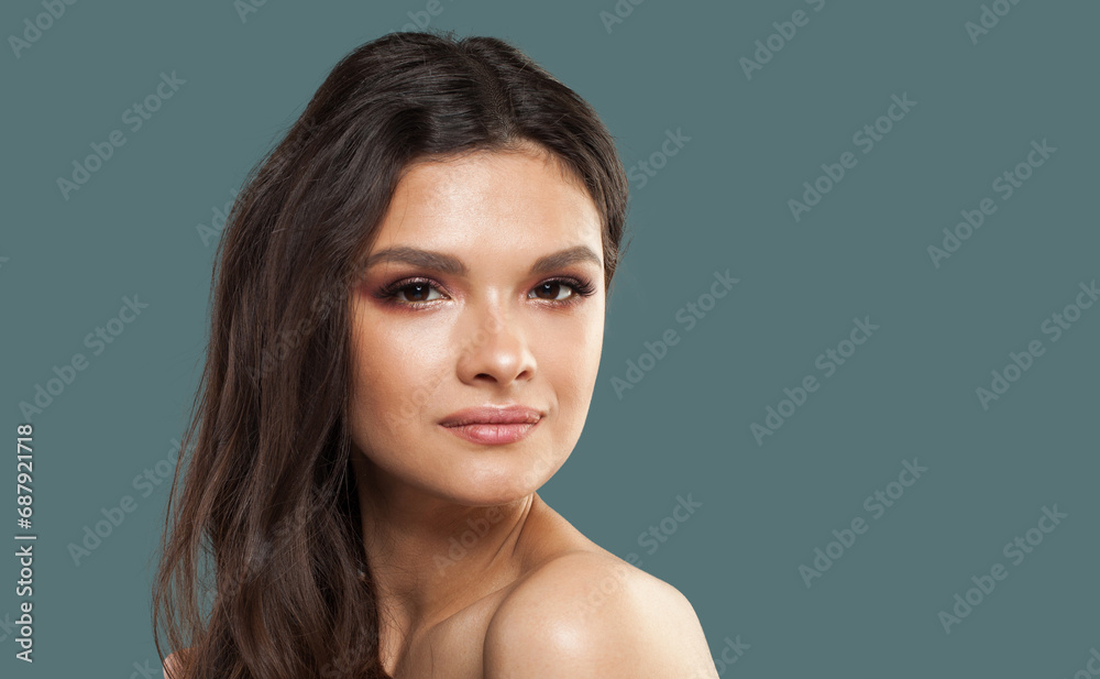 Healthy young model woman with wavy dark brown hairstyle and fresh clean shiny skin on blue studio background, fashion portrait. Skin care, hair care and cosmetology concept Healthy young model woman with wavy dark brown hairstyle and fresh clean shiny skin on blue studio background, fashion portrait. Skin care, hair care and cosmetology concept