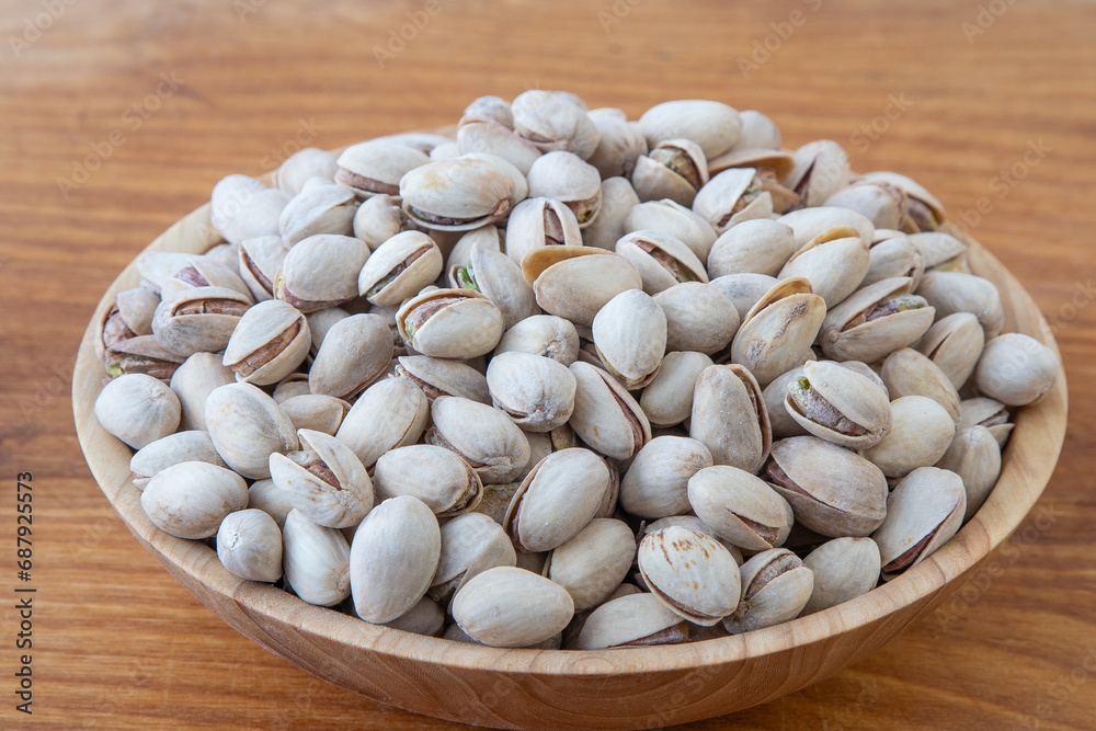 Pistachios in a wooden bowl. Wooden background. Healthy food Pistachios in a wooden bowl. Wooden background. Healthy food