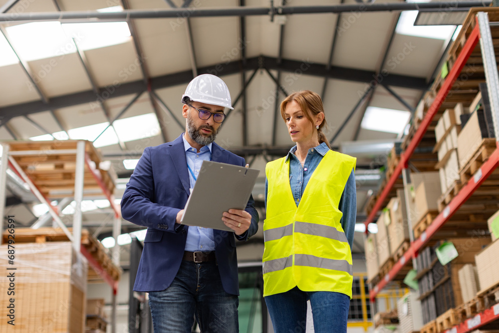 Female warehouse worker talking with production manager, discussing new order, preparing products for shipmennt, delivery, checking stock in warehouse. Female warehouse worker talking with production manager, discussing new order, preparing products for shipmennt, delivery, checking stock in warehouse.