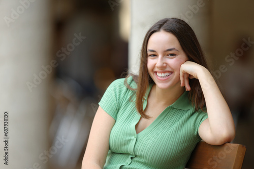 Happy woman laughing looking at camera on a bench
